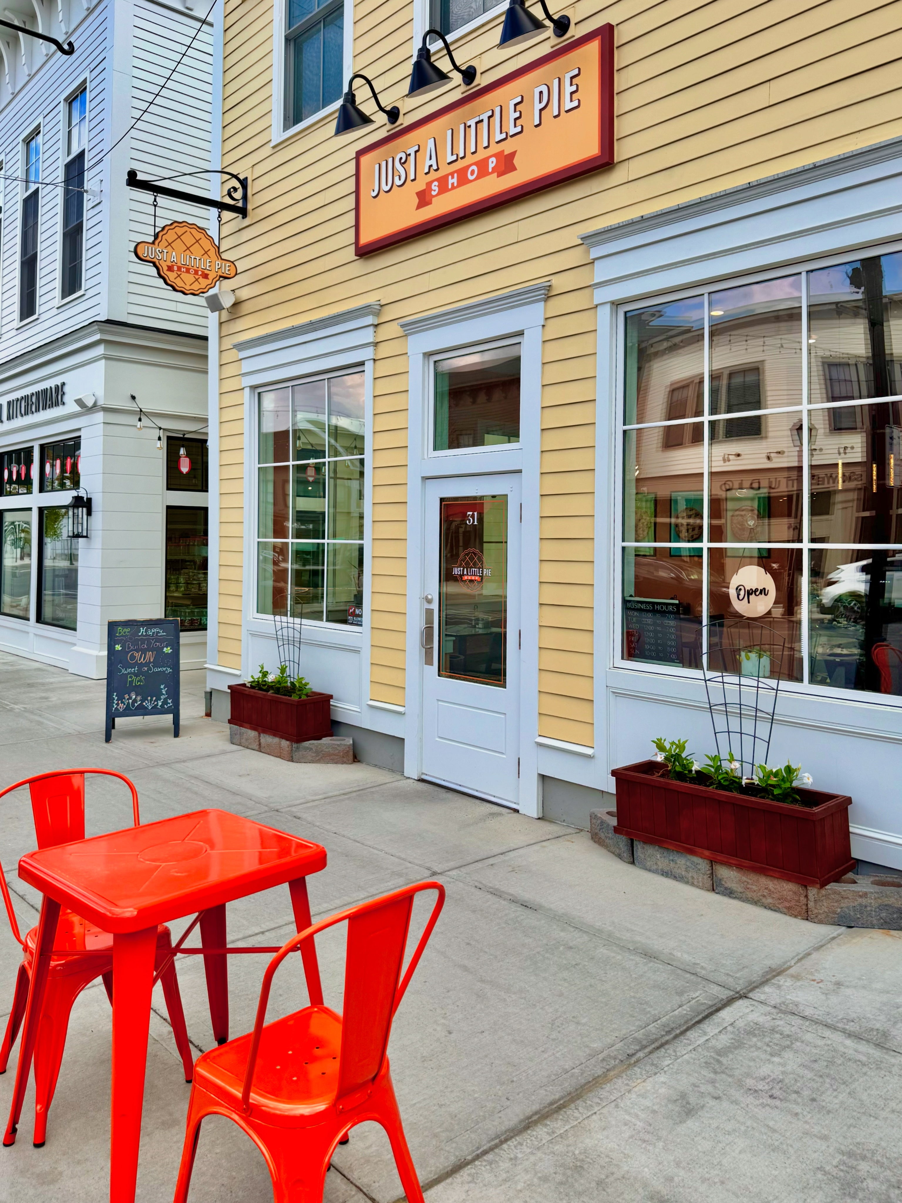 picture of a yellow building with orange chairs in front on the sidewak