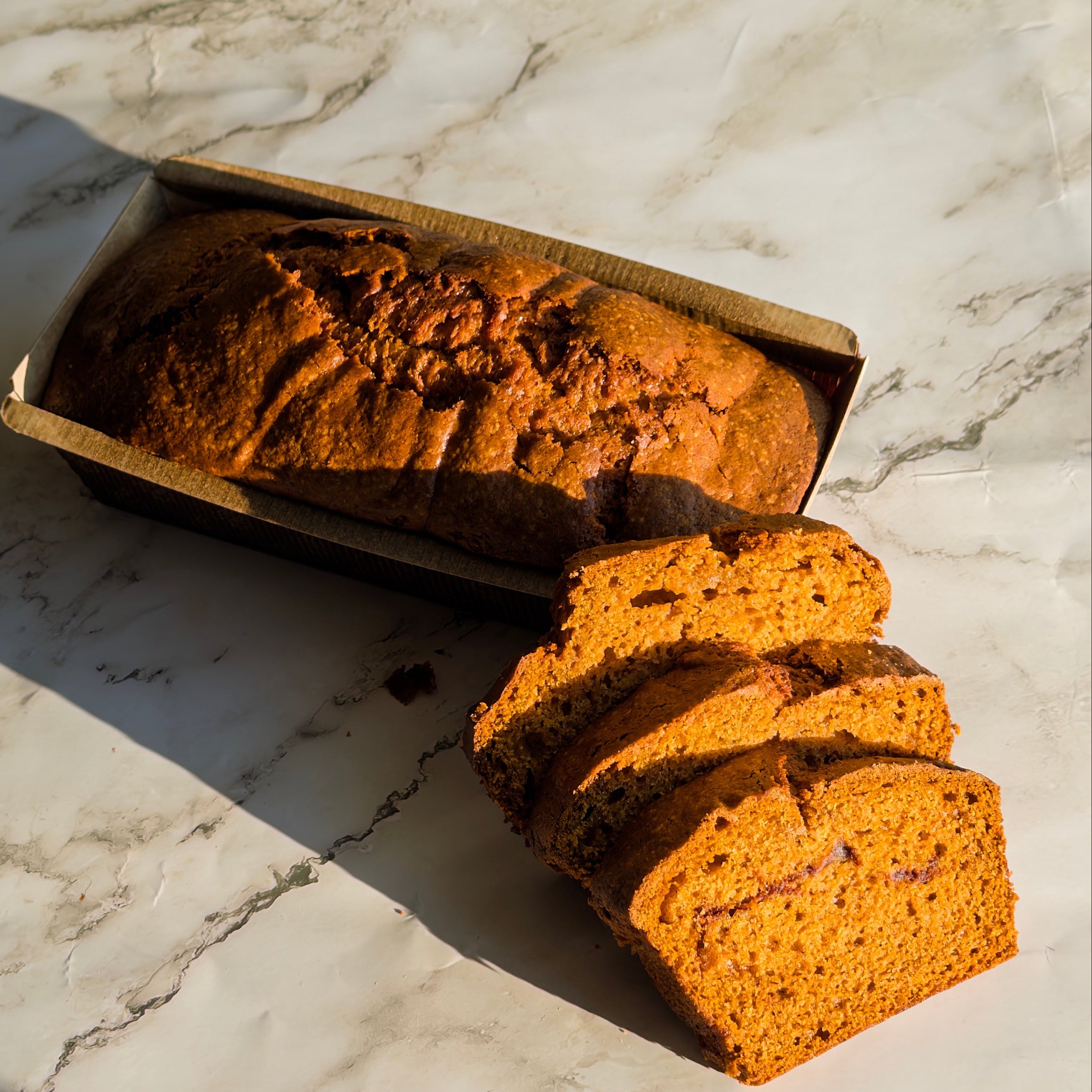 Loaf of pumpkin bread with slices on a marble surface