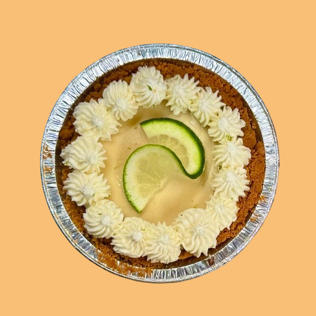 small key lime pie with a lime slice in the middle on an orange background