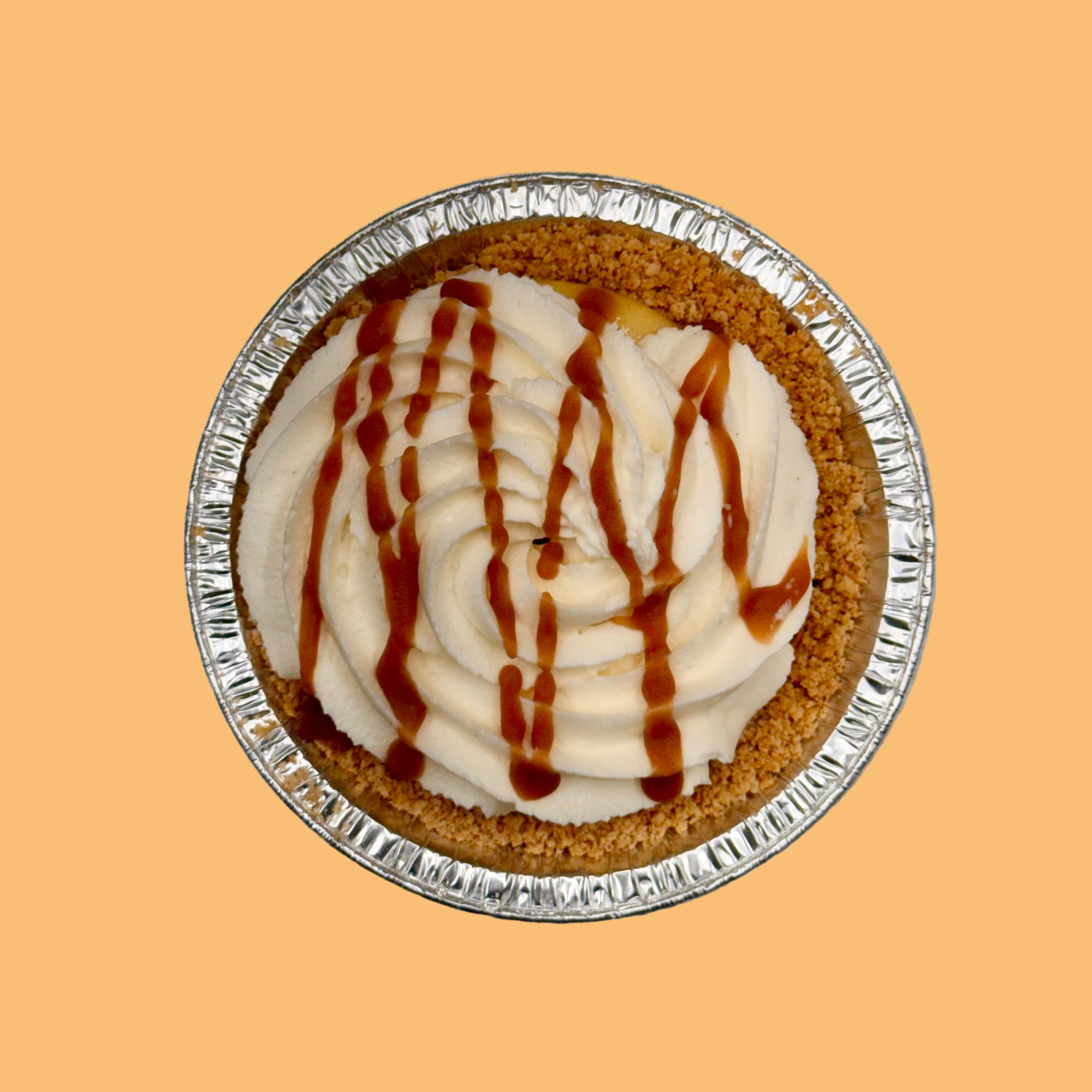 Small pie with whipped cream and caramel drizzle on a orange background