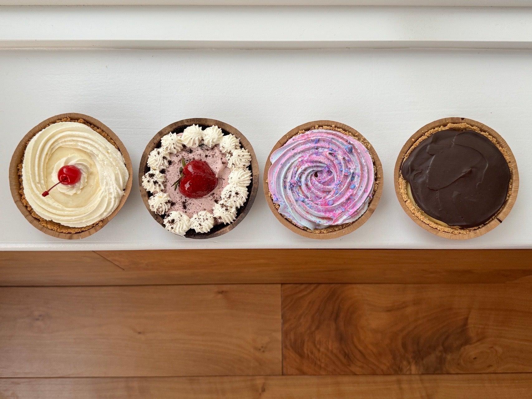 Four small dessert pies with different fillings on a white surface.